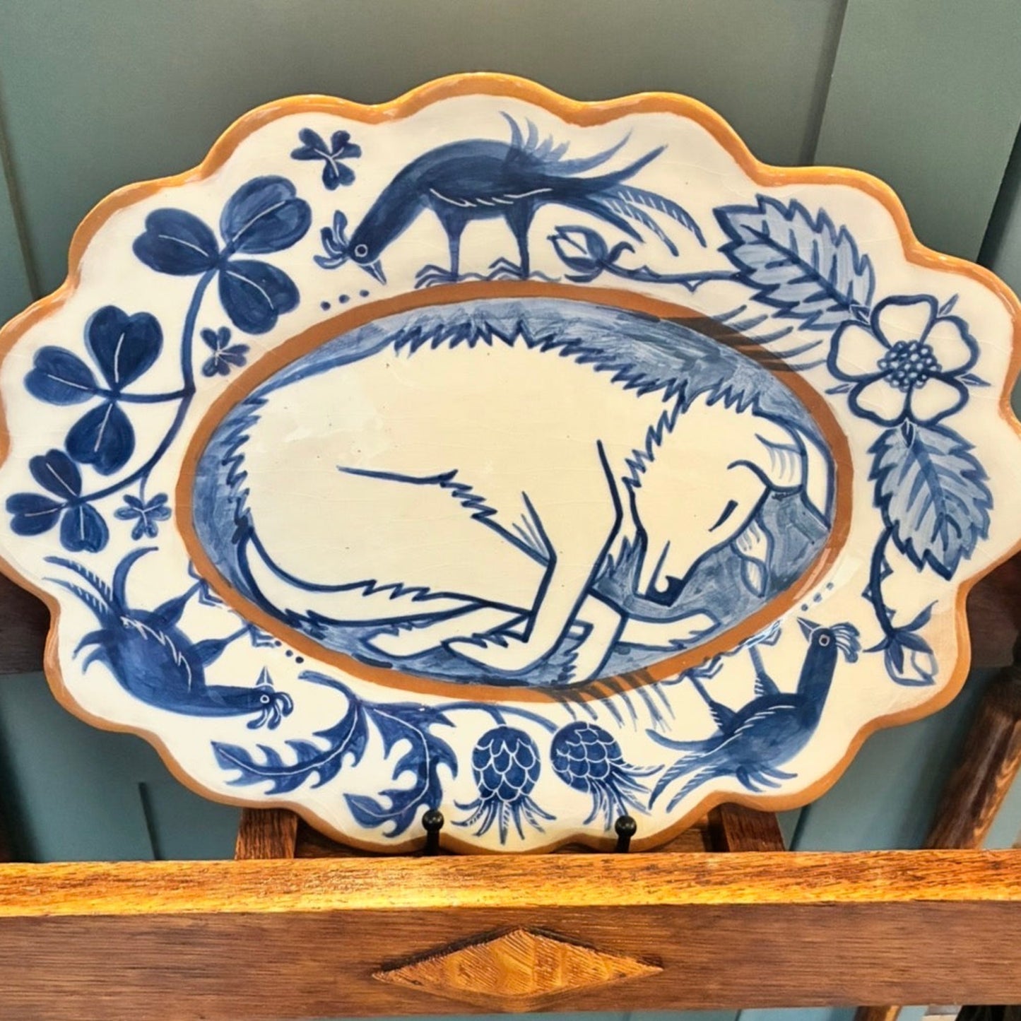 Decorative plate with blue animal design on a wooden stand