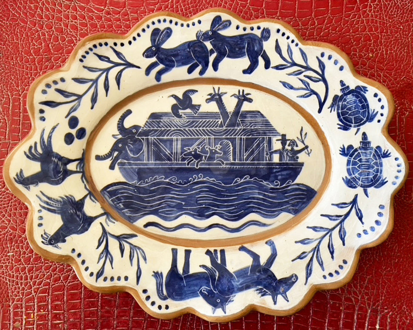 A large blue and white ceramic platter with a hand-painted design featuring animals and a boat, likely representing Noah's Ark.