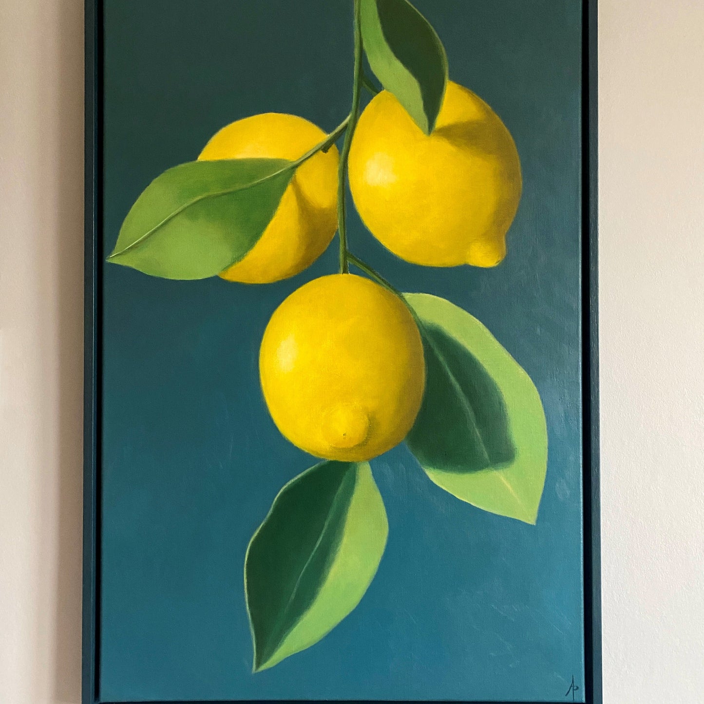 Framed artwork of three yellow lemons with green leaves on a teal background